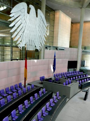 Der Bundestag von innen. Man sieht den Bundesadler und die leeren Stuhlreihen des Kabinetts.