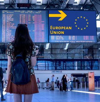 Frau am Flughafen schaut auf Schild mit Pfeil "European Union".