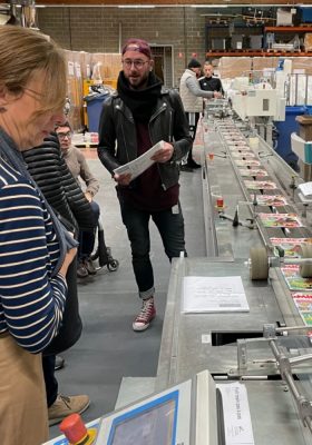 Das Projektteam im Inklusionsunternehmen Atelier Cambier in Charleroi. Auf einem Fließband werden Mickey Mouse-Hefte verpackt.