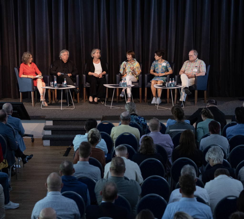 Foto vom Podium mit den Teilnehmer*innen der Diskussionsrunde